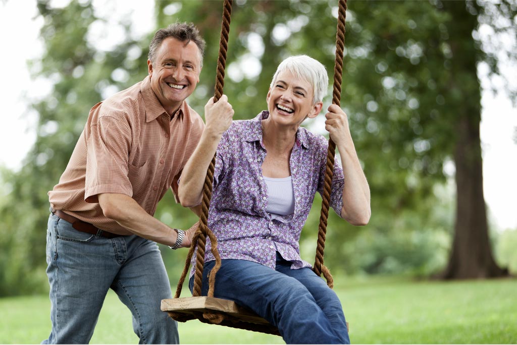 A man and woman playing on the swing.